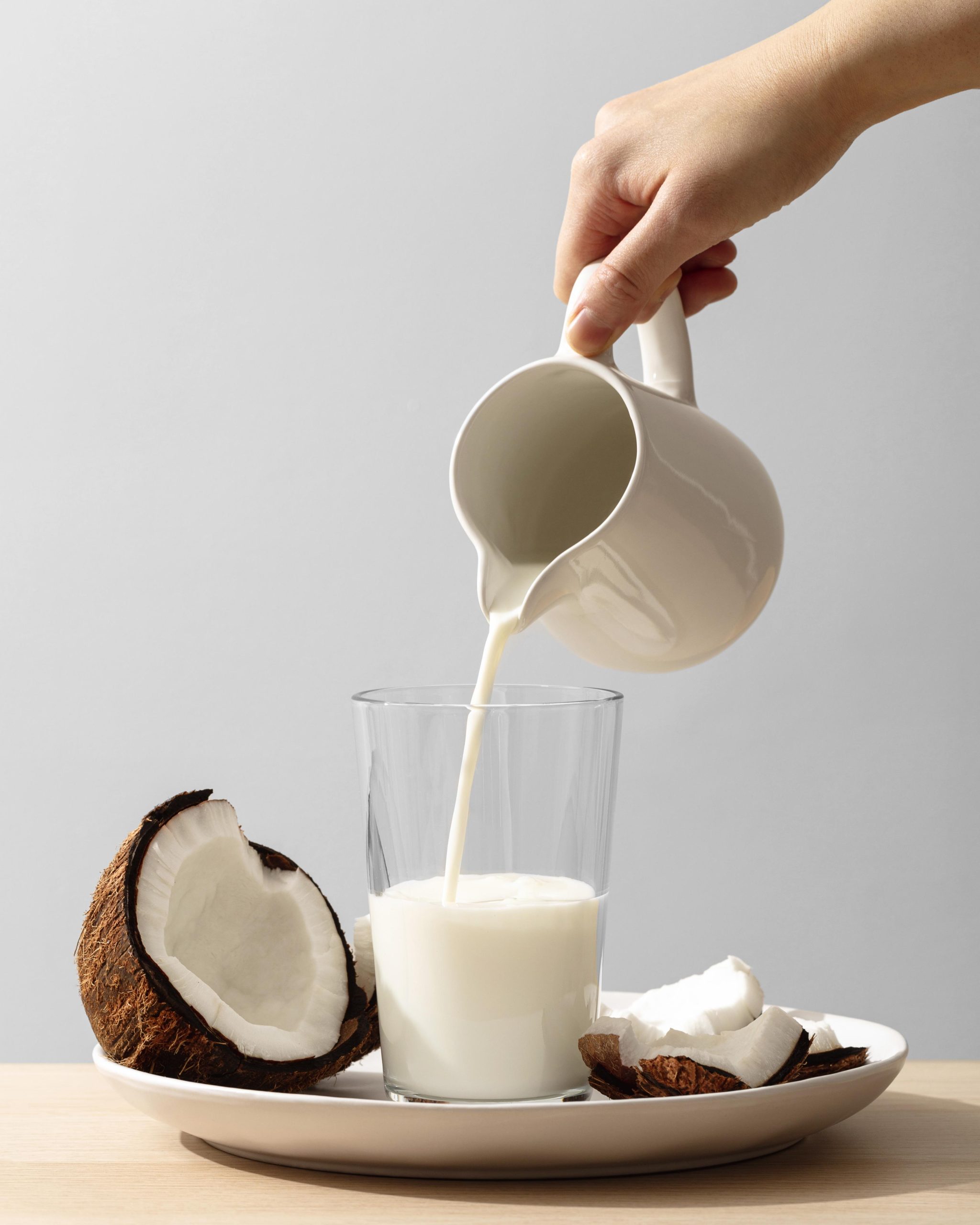 front-view-hand-pouring-coconut-milk-glass